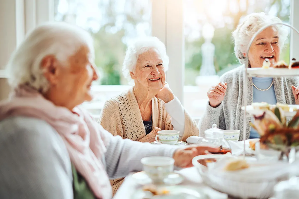 Ältere Person an einem Kaffeetisch