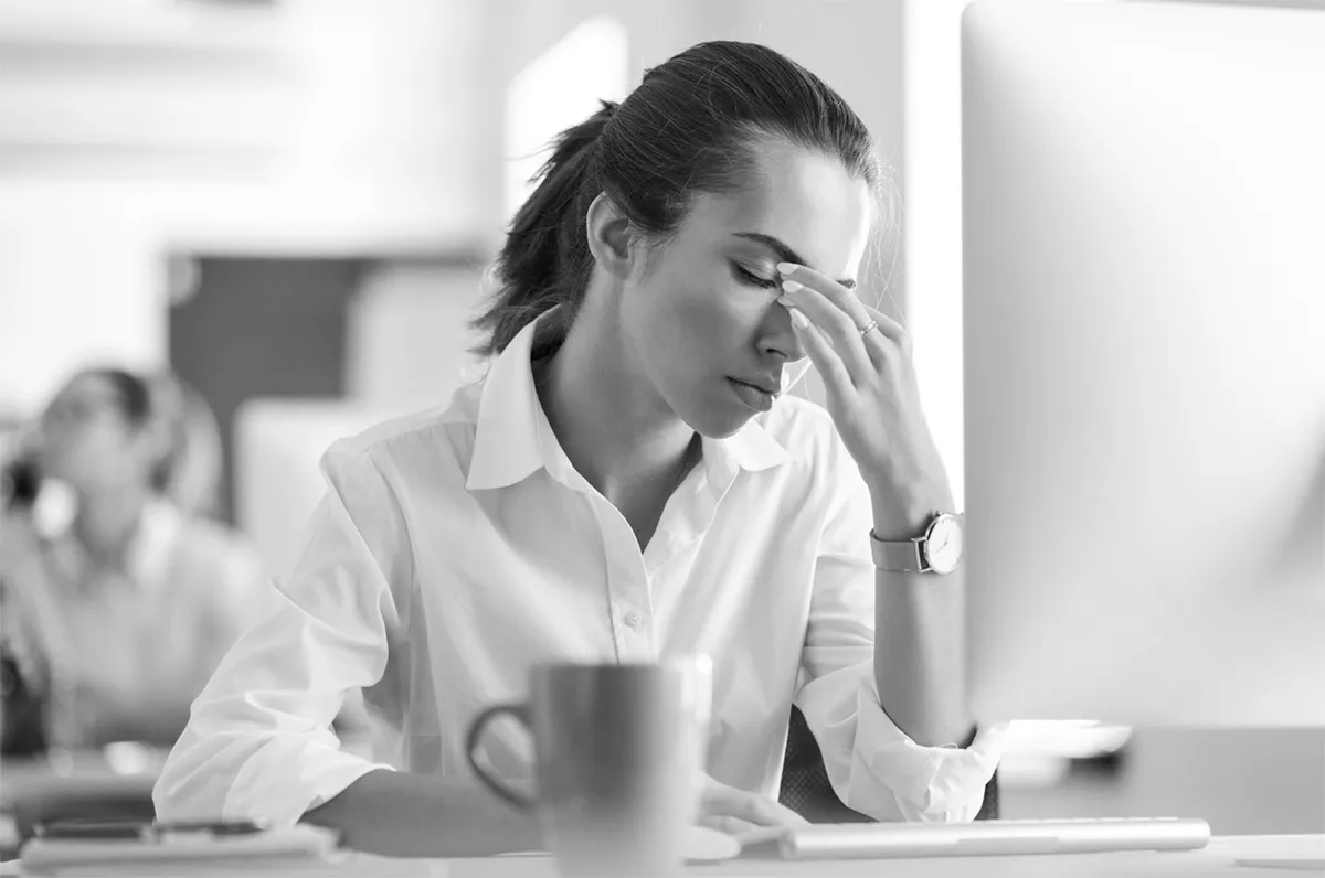 Eine weibliche Person in schwarz/weiß mit geschlossenen Augen und Hand vor der Stirn