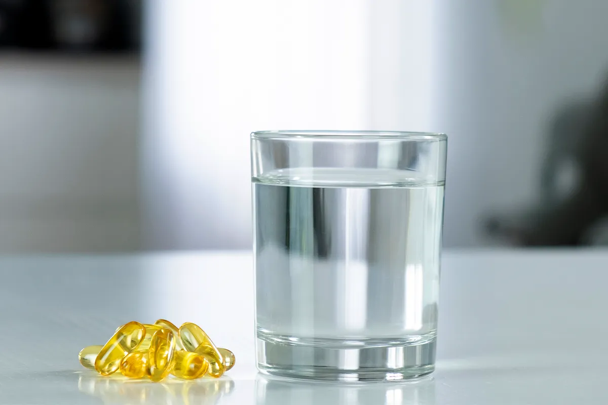 Empfohlene Dosis bei Schwangerschaft Säuglingsgesundheit Ein Glas Wasser mit transparenten, gelblichen Pillen