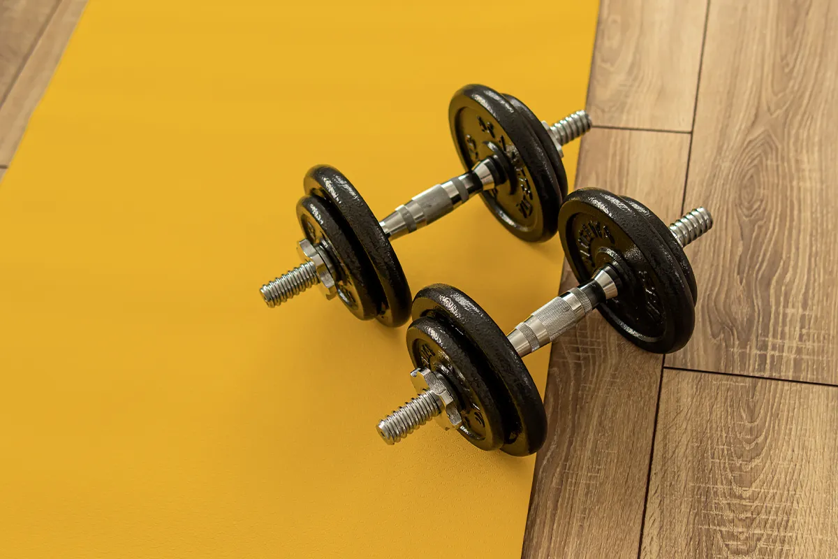 Zwei Hanteln auf gelblichen- und Holzboden