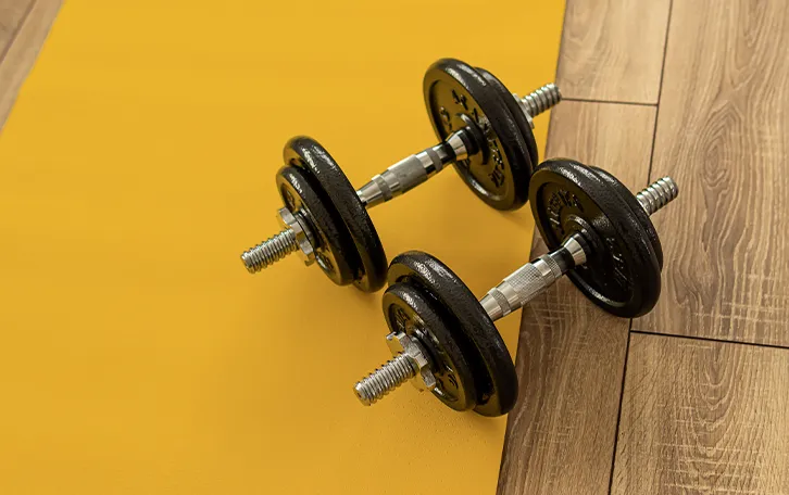 Zwei Hanteln auf gelblichen- und Holzboden
