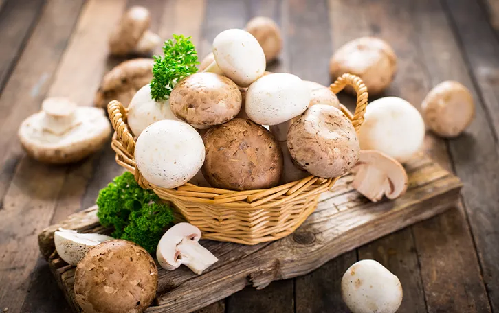 Lebensmittel mit hohem Vitamin D Gehalt Pilze Pilze in einem Korb und drum herum und mit Petersilie dekoriert