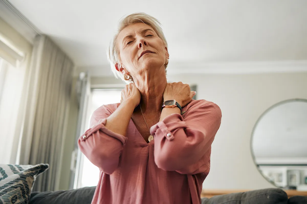 Müdigkeit Erschöpfung durch Vitamin D Mangel Eine ältere weibliche Person mit geschlossenen Augen hält sich mit beiden Händen den Nackenbereich