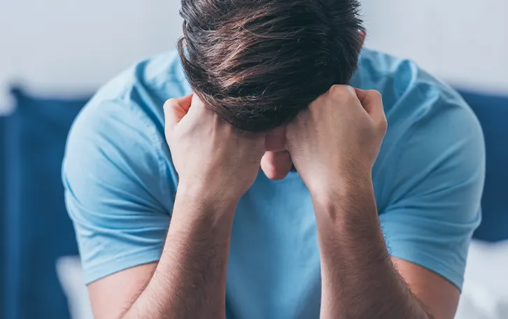 Vitamin D Mangel Symptom Stimmungsveränderungen Eine sitzende männliche Person mit dem Kopf auf beiden Fäusten gestützt