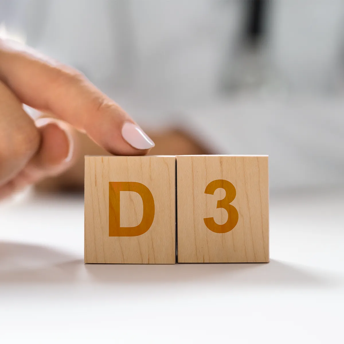 Vitamin D Mangel verstehen und vorbeugen Zwei Holzwürfel, die D3 zeigen und auf dem Würfel des D ist ein Zeigefinger