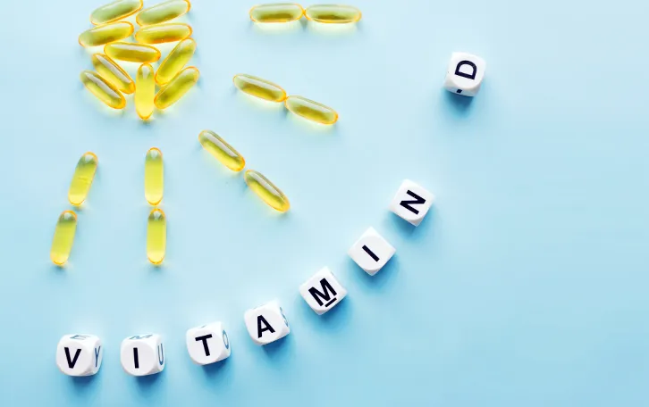 Wissenswertes was ist Vitamin D Eine Sonne mit Strahlen gelegt aus gelblichen Pillen und Würfeln mit dem Wort "Vitamin D" im Halbkreis gelegt