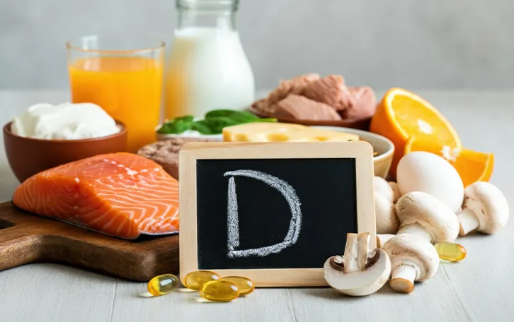 Wissenswertes zu Vitamin D in Lebensmitteln Eine Kollage aus unterschiedlichen Nahrungsmitteln mit einer Kreidetafel mit einem D drauf davor